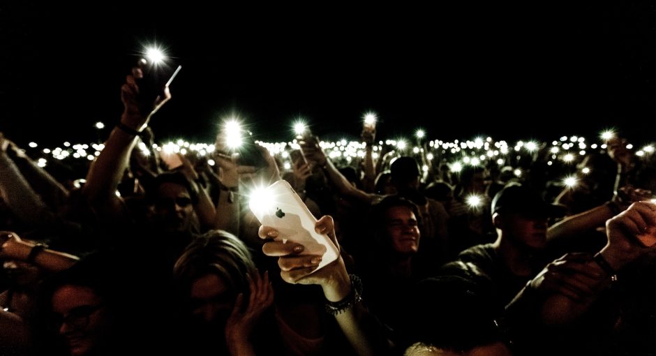 person holding phones with turned on flashlights